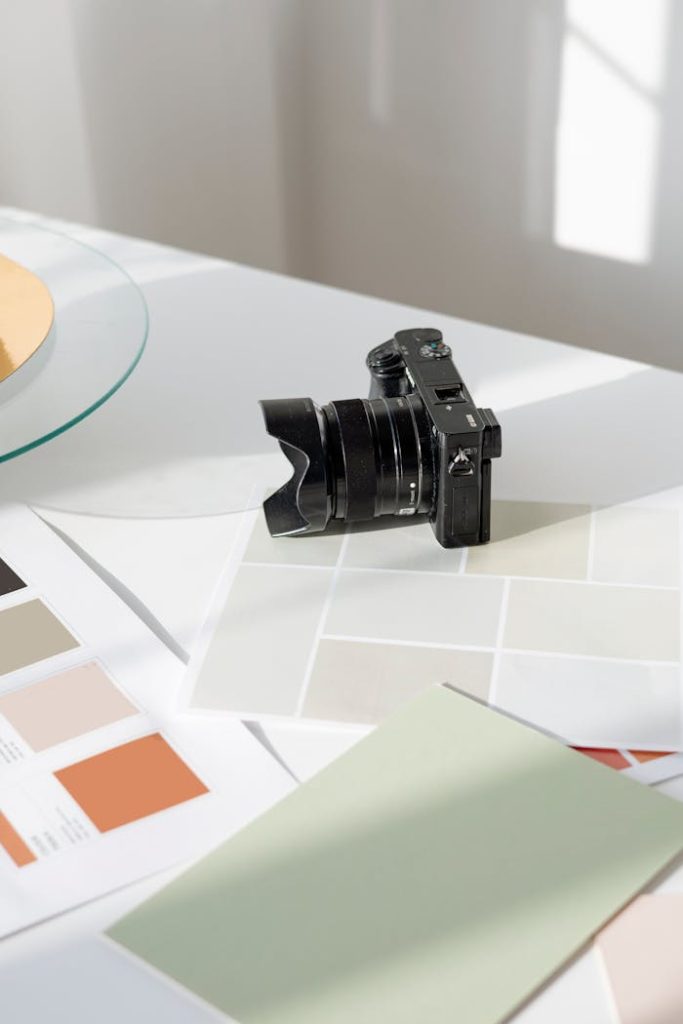 black-dslr-camera-on-white-table-7552741 Digital camera resting on a desk with color swatches and design materials.